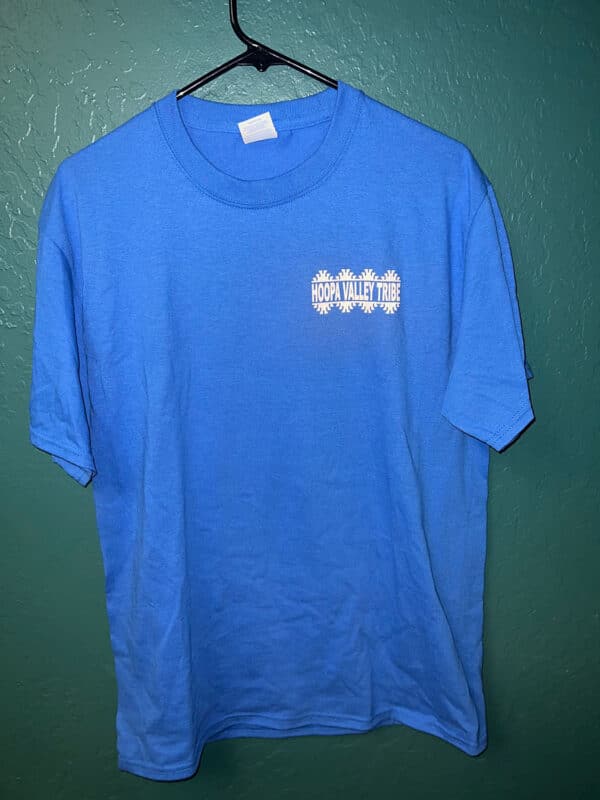 A dark blue tshirt hangs on a wall hook, with the Hoopa Valley Tribe logo visible