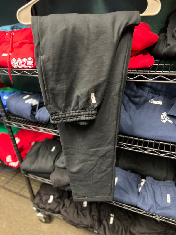 A pair of black sweatpants hangs on a rack