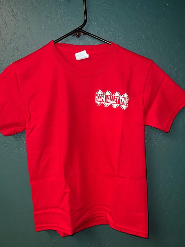 A red tshirt hangs on a wall hook, with the Hoopa Valley Tribe logo visible
