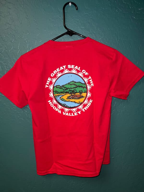 A red tshirt hangs on a wall hook, with the Hoopa Valley Tribe logo visible