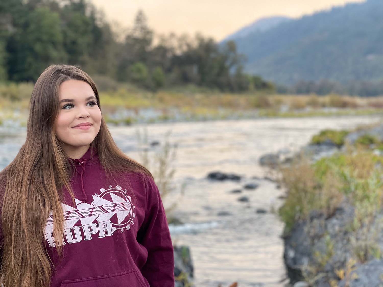 girl is standing next to a creek