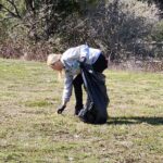 a person is picking up a piece of trash in the middle of a field