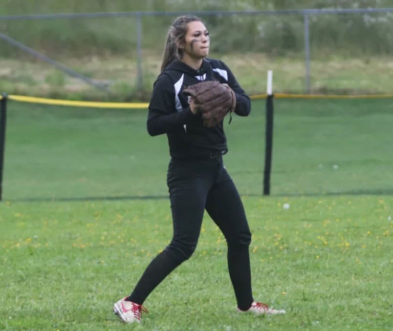 A girl plays softball in a field
